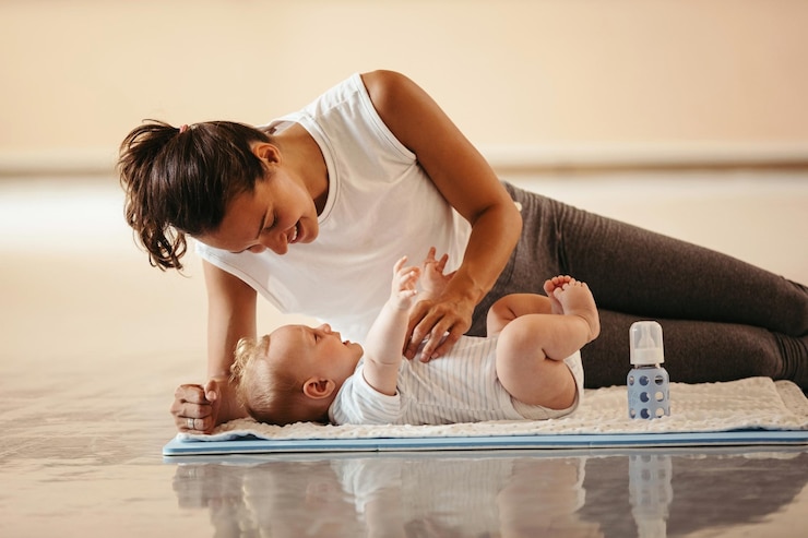 Jeune maman allongée avec son bébé durant une séance de yoga postnatal Nord Isère